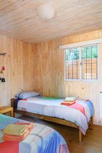 Habitación de madera con 2 camas y ventana en Glamping El Obrador Tilcara en Tilcara