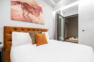 1 dormitorio con 1 cama blanca grande y una pintura en la pared en Royal Gold City Suites by Estia en Heraclión