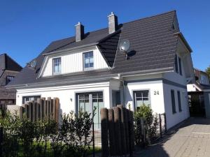 a white house with a black roof and a fence at Ostwestliebe in Zingst
