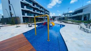 a pool with a slide in the middle of a building at Muro Alto Makia flat cinematográfico in Porto De Galinhas