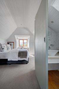 a white bedroom with a bed and a bathroom at Beautiful Abalone in Hermanus
