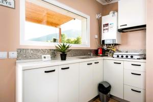 a kitchen with white cabinets and a window at RAI Lodges Bran - Predelut in Bran