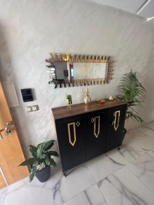 een kamer met een zwarte en gouden dressoir en een spiegel bij Chez Maria in Kenitra