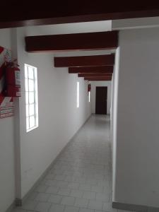 un couloir vide avec des murs blancs et une fenêtre dans l'établissement Departamentos calle 8, à Necochea