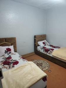 ein Schlafzimmer mit zwei Betten mit roten Blumen drauf in der Unterkunft Maison sahara in Ad-Dakhla