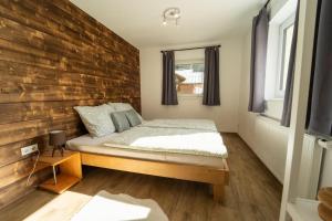 een slaapkamer met een bed en een houten muur bij Haus Faninger - SUMMERCARD included in Kaprun