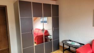 un gran armario gris con un sofá rojo en una habitación en Sehr gemütliches und gepflegtes Zimmer 8 Km von Bern-City, en Köniz