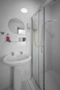a white bathroom with a sink and a shower at Cozy Apartment 3 - Free Parking & Long Stays in Blackpool