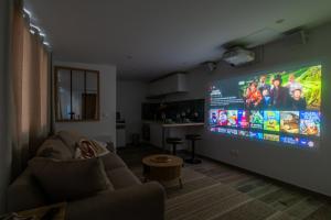 uma sala de estar com uma grande televisão de ecrã plano na parede em Éden Spa & Cinéma em Les Essarts-le-Roi