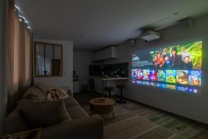 a living room with a large flat screen tv on a wall at Éden Spa & Cinéma in Les Essarts-le-Roi