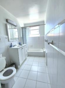 a white bathroom with a toilet and a sink at Lovely 5Bedroom apartment in NYC! in New York
