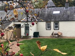 a white house with a picnic table in a yard at Barns Bothy in Peebles