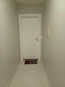 un pasillo con una puerta blanca en una habitación blanca en Apartamento aconchegante perto da praia, en Balneário Camboriú