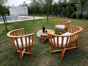 3 sillas de madera y una mesa con una botella. en Camino Marquez en Santiago del Estero