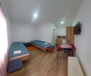 a room with two beds and a desk and a table at Apartmani Popović in Knjazevac.