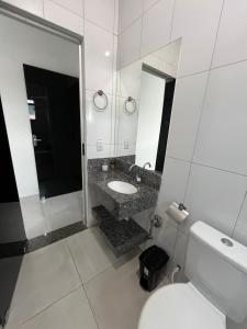 a bathroom with a toilet and a sink and a mirror at Apto Aconchego Capitólio in Capitólio