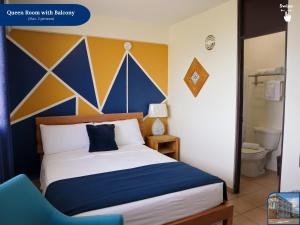 1 dormitorio con 1 cama con pared azul y amarilla en West Coast Inn's en Boqueron