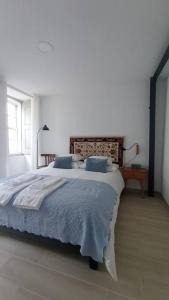 a white bedroom with a large bed with blue pillows at Apartamento da Torre in Guarda