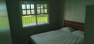 a bedroom with a bed and an open window at ponta do papagaio in Palhoça