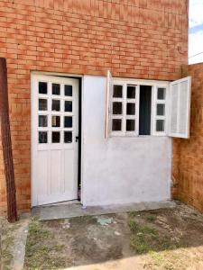 een witte deur en raam naast een bakstenen gebouw bij Kitnet a 150m da praia in Rio Grande