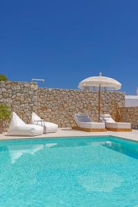 a swimming pool with chairs and an umbrella at Milos Villas Complex in Pefki