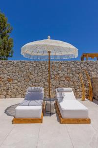 2 Betten und ein Sonnenschirm auf einer Terrasse in der Unterkunft Milos Villas Complex in Pefki Rhodes