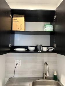 una cocina con fregadero y una caja en un estante en Nice and Cozy guest house en Miami