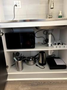 a kitchen shelf with a microwave and some utensils at Nice and Cozy guest house in Miami