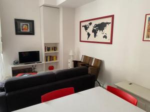 ein Wohnzimmer mit einem schwarzen Sofa und roten Stühlen in der Unterkunft I Marici in Pavia