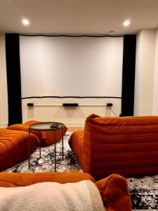 une pièce avec deux canapés et un grand écran de projection dans l'établissement Le Singapour - Cottage Resort - Brownsburg-Chatham, à Brownsburg 77 autres photos