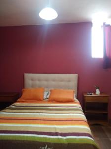 1 dormitorio con pared morada y 1 cama con almohadas de color naranja en Balcones de Zorritos, en Bocapán