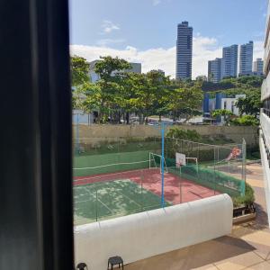 una pista de tenis vista desde la ventana de un edificio en Apartamento no Ondina Apart Hotel, en Salvador