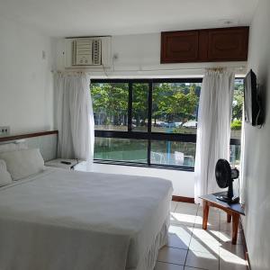 a bedroom with a bed and a large window at Apartamento no Ondina Apart Hotel in Salvador