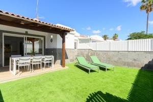 ein Garten mit grünem Rasen, einem Tisch und Stühlen in der Unterkunft Beachside hideaway Gran Canaria in San Bartolomé de Tirajana
