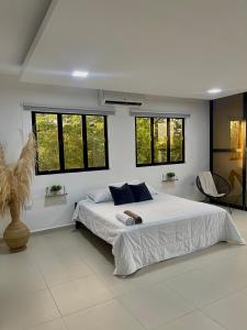 a bedroom with a large white bed with windows at Casa Del Río in Montería