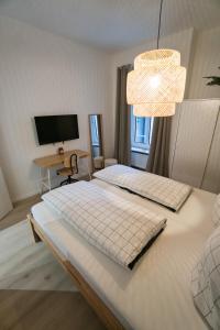 2 Betten in einem Zimmer mit einem TV und einem Kronleuchter in der Unterkunft Goethe-Suites: Premium 4 Person Worms city centre Appartment in Worms