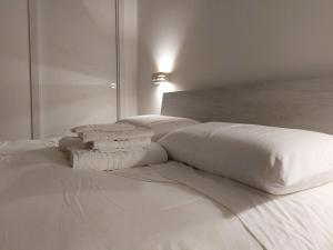 un letto bianco con lenzuola e cuscini bianchi di l'aira ecchia - ospitalità rurale a Lecce