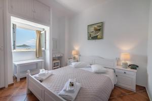 a white bedroom with a large bed and a window at Agali bay hotel in Tinos