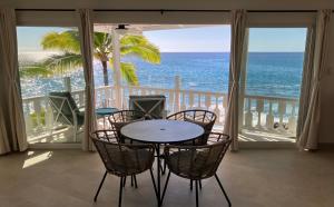 una mesa y sillas en un balcón con vistas al océano en Kona Tiki Hotel, en Kailua-Kona