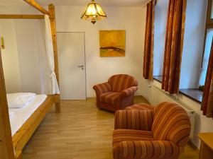 ein Zimmer mit 2 Stühlen, einem Bett und einem Schlafzimmer in der Unterkunft Schlossschänke Friedenfels in Friedenfels