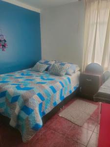 1 dormitorio con 1 cama con pared azul en MUNAYCHA`S WASI, en Cusco