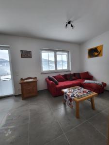 a living room with a red couch and a table at Ferienwohnungen Maderebner in Gröbming