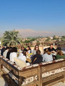 un grupo de personas sentadas en una mesa comiendo en Moonlight Home, en Luxor