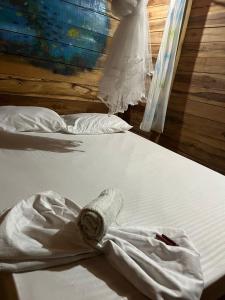 two beds with white sheets and a dress on them at the mompe beach hostal in La Poza