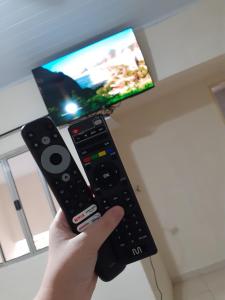 a person holding a remote control in front of a tv at Espaço igor in Aparecida