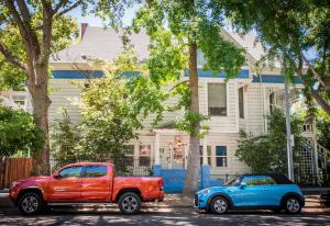 a red truck and a blue car parked in front of a house at IreneHouse Victorian INN in Sacramento