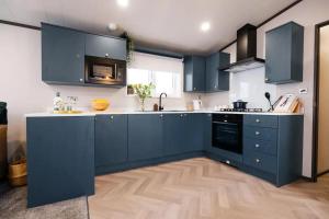 a kitchen with blue cabinets and a wooden floor at Heather William Luxury Lodge in Woodhall Spa in Woodhall Spa