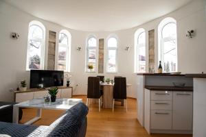a living room with a table and a kitchen with windows at Kula Centar in Trebinje