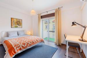 a bedroom with a bed and a desk and a window at Cosy Remodeled apartment in the City center in Fundão