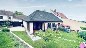 a house with a black roof and a yard at Dům Pálava in Perná